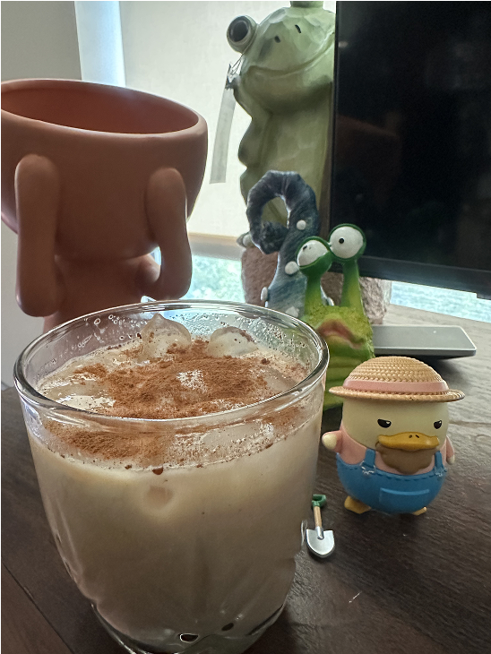 A chai latte and small figurines on a desk